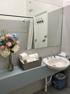 baño con lavabo y jarrón de flores en Adelaide Pulteney Motel en Adelaida