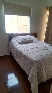a bedroom with a bed with a white comforter and a window at Casa en cineguilla in Cieneguilla