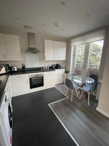 cocina con armarios blancos, mesa y sillas en Modern 1-Bedroom Apartment close to City Airport en Londres