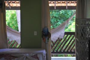 a bedroom with a porch with a bed and a window at Pousada Agua Marinha in Imbassai
