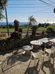 a patio with tables and chairs and a stone wall at Umi no Mieru Ie Ocean View in Nishinoomote