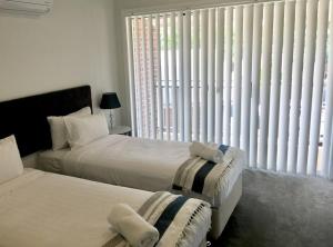 ein Schlafzimmer mit zwei Betten und einem großen Fenster in der Unterkunft Wagga Apartments #2! in Wagga Wagga