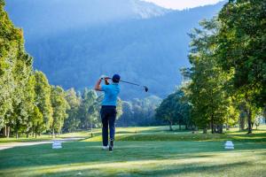 Ein Mann, der einen Golfklub auf einem Golfplatz schwingt. in der Unterkunft Handara Golf & Resort Bali in Bedugul