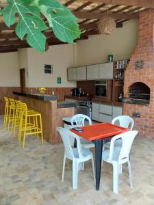 kuchnia z czerwonym stołem i białymi krzesłami w obiekcie Chácara aconchego do Valle w mieście Petrolina