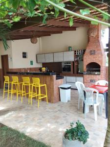a patio with a bar with yellow chairs and a kitchen at Casa de temporada Petrolina-PE in Petrolina