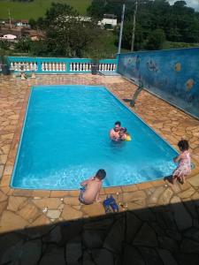 a man and two children playing in a swimming pool at Chácara Oliveira in Socorro