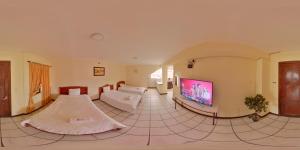 uma sala de estar com um sofá e uma televisão de ecrã plano em Hotel 4 Mundos em Cuenca