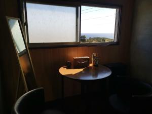 einen kleinen Tisch in einem Zimmer mit Fenster in der Unterkunft Umi no Mieru Ie Ocean View in Nishinoomote