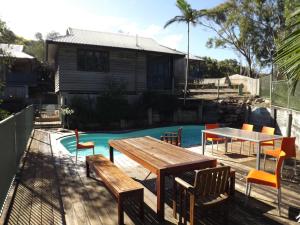 a deck with a table and chairs next to a pool at Fraser Island Retreat in Fraser Island