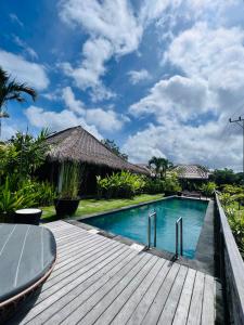 una piscina en una villa con terraza de madera en La Reserva Villas Bali, en Jimbaran