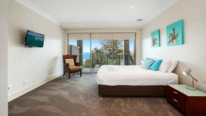 a bedroom with a bed and a tv and a chair at Unit 18 - 3 Bed Part Ocean View in Terrigal