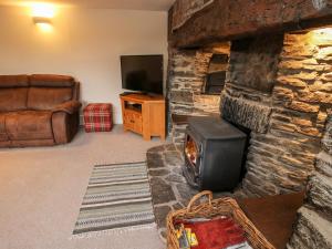 a living room with a stone fireplace and a television at Bicton Cottage in Acton