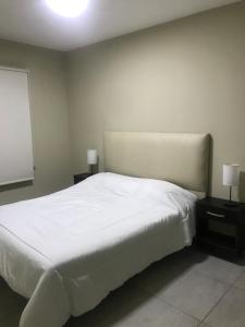 um quarto com uma grande cama branca com duas mesas de cabeceira em Departamento nuevo em Mendoza