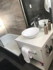 uma casa de banho com um lavatório branco e uma banheira em Departamento nuevo em Mendoza
