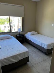 2 camas en una habitación con ventana en Departamento nuevo en Mendoza