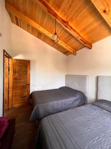 1 Schlafzimmer mit 2 Betten und Holzdecke in der Unterkunft Cabaña "Alexa", en el corazón del bosque de Mazamitla in Mazamitla