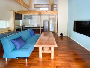 sala de estar con sofá azul y mesa de madera en Yonehara Beach Stay LUANA - Vacation STAY 38711v en Fukai