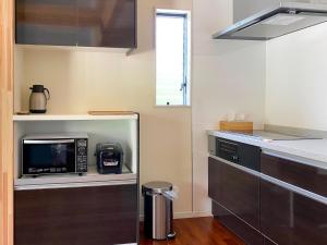 a kitchen with a microwave oven and a stove at Yonehara Beach Stay LUANA - Vacation STAY 38711v in Fukai