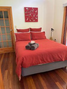 a bedroom with a red bed with red pillows at Kin Kin Cottage Retreat in Kin Kin