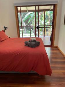 a bedroom with a red bed and a large window at Kin Kin Cottage Retreat in Kin Kin