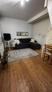 sala de estar con sofá negro y suelo de madera en Apartment Wanha Kartano, en Kokkola
