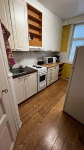 a kitchen with white cabinets and a wooden floor at Apartment Wanha Kartano in Kokkola