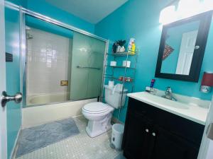 uma casa de banho azul com um WC e um lavatório em Private quiet room with shared Bathroom,kitchen,living and dining area em Clinton