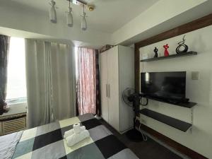 um quarto com uma cama e uma televisão na parede em Azure Urban Resort with WIFI and Netflix em Manila