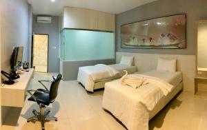 a hotel room with two beds and a desk at Hip Hope Hotel Banda Aceh in Banda Aceh