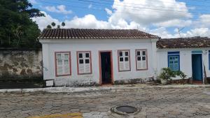una pequeña casa blanca con una puerta roja en MAEVE Quarto Mata en Goiás