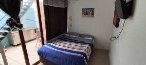 Cama pequeña en habitación con TV en Casa de Verano, en Iquique