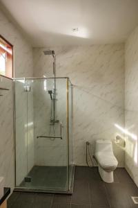 La salle de bains est pourvue d'une douche en verre et de toilettes. dans l'établissement Sembilan Langkawi, à Kampung Padang Masirat