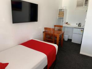 a bedroom with a bed and a desk and a television at Royal Motel Tenterfield in Tenterfield