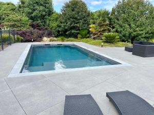 a swimming pool with two chairs on a patio at Cedar Park Bed & Breakfast in Hamilton