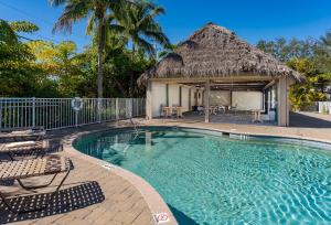 a resort swimming pool with a thatch roof at -The Bonita Paddle Efficiency- Your Home Away From Home in Paradise condo in Bonita Springs