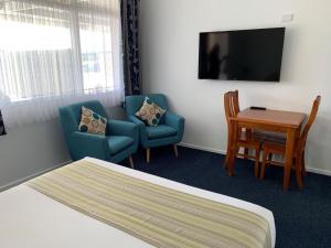 a hotel room with a bed and two chairs and a table at Royal Motel Tenterfield in Tenterfield