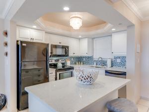 フォートマイヤーズビーチにあるTwo-Bedroom Apartmentの白いキャビネットとカウンタートップを備えたキッチン