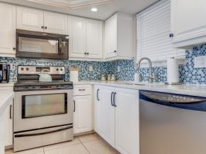 フォートマイヤーズビーチにあるTwo-Bedroom Apartmentの白いキャビネットとシンクのあるキッチン