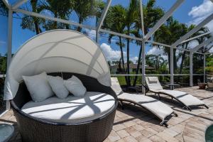 einen Korbstuhl und Stühle auf einer Terrasse in der Unterkunft Barefoot Hideaway, with Spa and Pool home in Bonita Springs