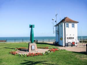 a small lighthouse with a green statue in the grass at The Beehive in Mundesley