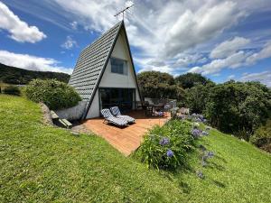 a house with a gambrel roof sitting on a wooden deck at Pohutukawa Coastal Chalets in Coromandel Town