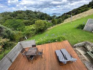 a wooden deck with a table and chairs on it at Pohutukawa Coastal Chalets in Coromandel Town