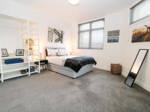 een witte slaapkamer met een bed en een spiegel bij Apartment 7 in Lowestoft