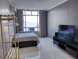 a bedroom with a bed and a flat screen tv at Mirante de São Vicente in São Vicente