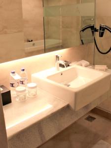 a bathroom with a white sink and a mirror at ASTON Pluit Hotel & Residence in Jakarta