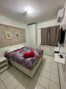 Un dormitorio con una cama con una almohada roja. en Flat Biarritz - Ao lado da Litoranea - Ferreira Hospedagens, en São Luís
