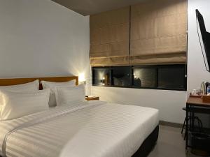 1 dormitorio con 1 cama blanca grande y ventana en d'primahotel Lagoi Bintan, en Lagoi