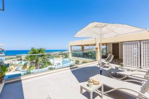 patio z parasolem i krzesłami oraz oceanem w obiekcie Radama A1 w mieście Sfakaki