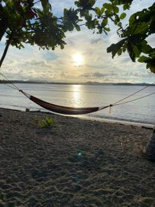 a hammock on a beach near the water at Family Cabana at Amihan Surf Cabanas in General Luna
