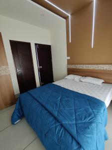 a bedroom with a large blue comforter on a bed at Eva Meadows in Kollam